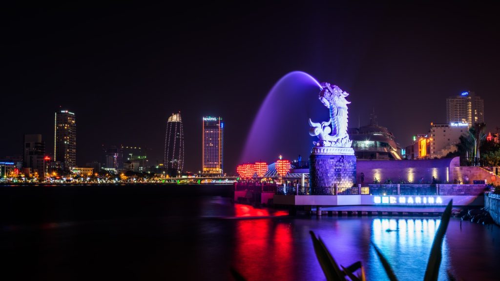 A photo of Da Nang at night, featuring a dragon statue and a bridge.